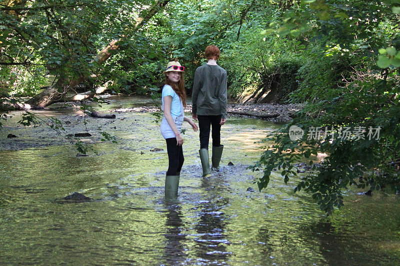 男孩和女孩在河边、林地里玩耍/涉水